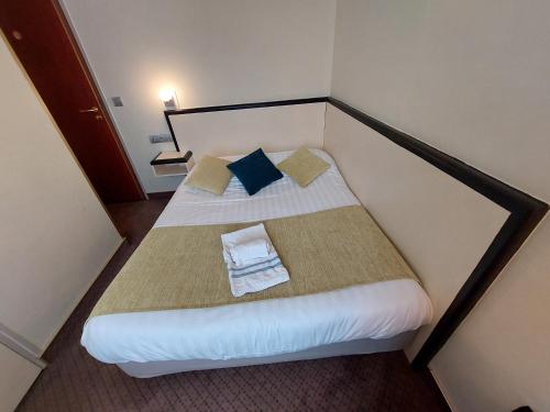 a small room with a bed with two pillows at Logis Hôtels - Hôtel et Restaurant Le Lion d'Or in Gramat