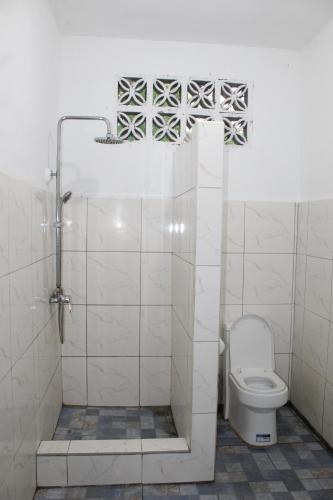ein weißes Bad mit einem WC und einer Dusche in der Unterkunft Crossroads Beach House in Sablayan