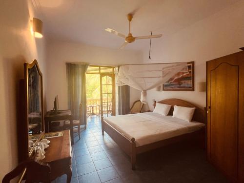 a bedroom with a bed and a table and a television at Muthumuni Ayurveda River Resort in Aluthgama