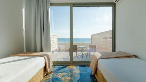 two beds in a room with a view of the ocean at Ninos Grand Beach Resort in Kastrosikia