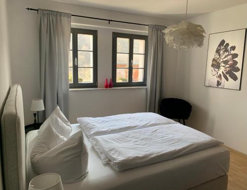 a white bed in a bedroom with two windows at Ferienwohnung Geißler in Radebeul