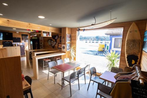 un restaurante con mesa, sillas y tabla de surf en Carving Surf Hostel, en San Esteban de Pravia