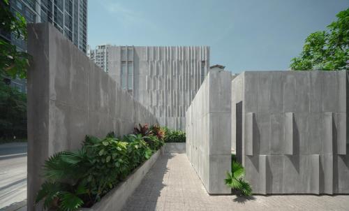 a concrete wall with plants in front of a building at Nidhra Boutique Hotel Bangkok Sukhumvit in Bangkok