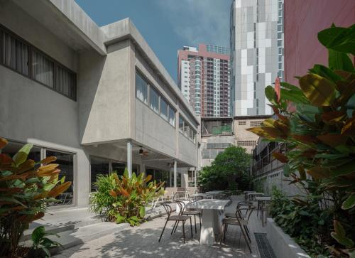 an outdoor patio with tables and chairs and buildings at Nidhra Boutique Hotel Bangkok Sukhumvit in Bangkok