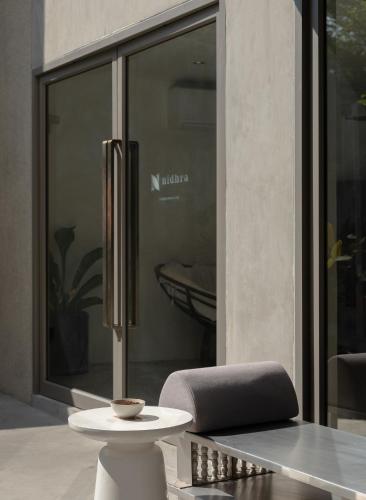 a chair and a table in front of a window at Nidhra Boutique Hotel Bangkok Sukhumvit in Bangkok
