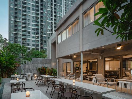 a patio with tables and chairs and tall buildings at Nidhra Boutique Hotel Bangkok Sukhumvit in Bangkok