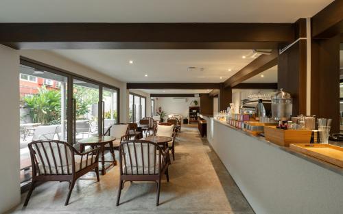 a restaurant with tables and chairs and a counter at Nidhra Boutique Hotel Bangkok Sukhumvit in Bangkok