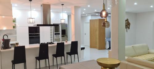 uma cozinha e sala de estar com um bar com cadeiras pretas em Cazinos Apartamento 2 em Praia