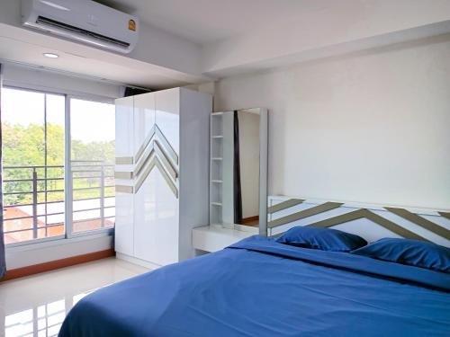 a bedroom with a blue bed and a balcony at Wangkaew Suite Hotel in Phitsanulok