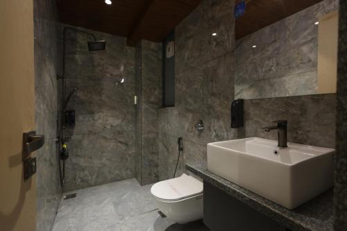 a bathroom with a sink and a toilet and a shower at Hotel Sapphire 26 in Surat