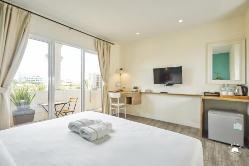 1 dormitorio con 1 cama, TV y mesa en Talay Hotel and Villa Cha-am en Cha Am