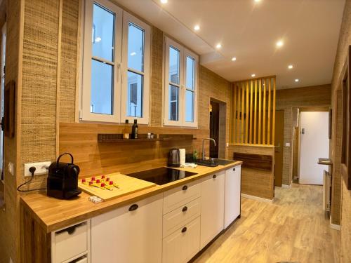 a kitchen with white cabinets and wooden floors and windows at Rouen Hypercentre - Le relais des Amis in Rouen
