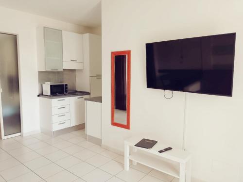 a kitchen with white cabinets and a tv on the wall at ALBACHIARA INN Residence Apartments in Ameglia