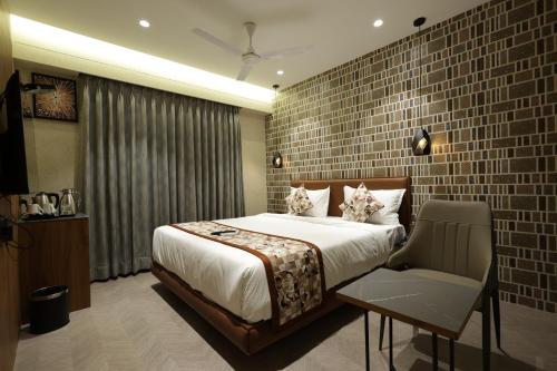 a bedroom with a large bed and a chair at Hotel Sapphire 26 in Surat