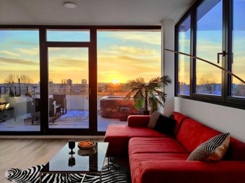 a living room with a red couch and a large window at Maisonette-Penthouse inklusive Whirlpool über den Dächern von Magdeburg in Magdeburg