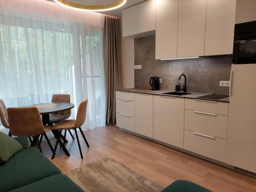 a kitchen with white cabinets and a table with chairs at Gold holiday Apartments - "Fairy Tale Forest" Mano jūra 2 in Palanga