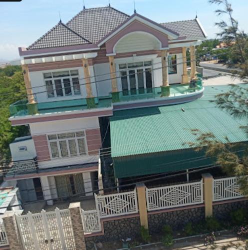 a large house with a green roof and a fence at Nhà Nghỉ Đăng Miên in Thôn Hiếu Thiện