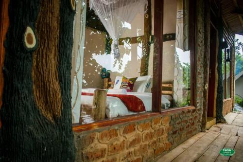 Schlafzimmer mit einem Bett in einem Glasfenster in der Unterkunft Sipi Falls Cottages in Sipi