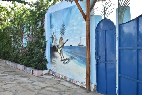 a mural on the side of a building with a blue door at Pineapple House in Nungwi
