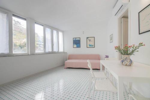 a white living room with a pink couch and windows at Al Ciglio Holiday House Amalfi Coast in Scala