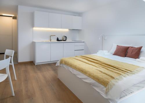 a white bedroom with a bed and a sink at Primus apartments in Ljubljana