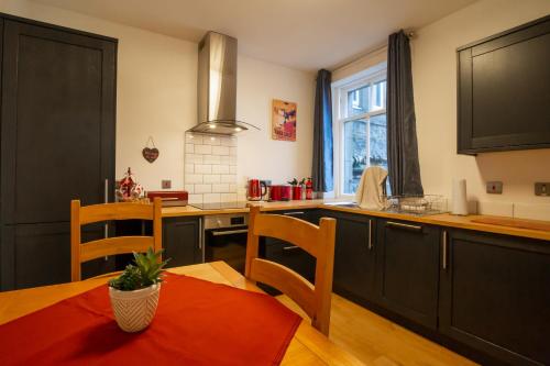 eine Küche mit schwarzen Schränken sowie einem Tisch und Stühlen in der Unterkunft 5 wheelhouse apartments in Lochinver