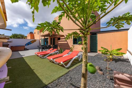 a patio with lounge chairs and a palm tree at Sunrise Surf House, Big Garden, Hot Tub, Parking, super-fast free Wi-Fi in Corralejo