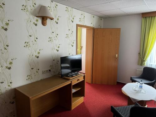 a room with a desk with a television and a room with a door at Goldene Krone in Belgershain