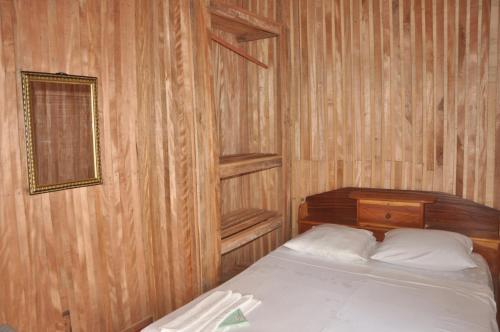 a bedroom with a bed and a wooden wall at Kribi-Lodge in Kribi