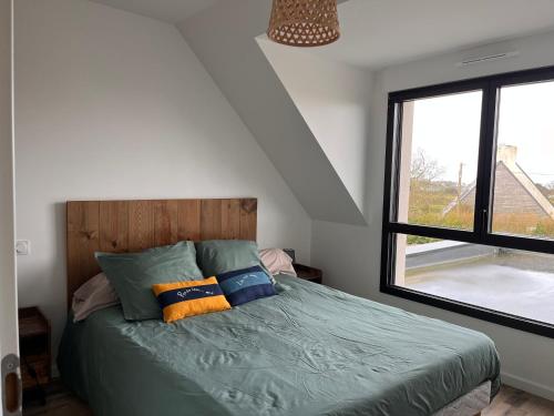 - une chambre avec un lit doté d'oreillers et d'une fenêtre dans l'établissement Maison de vacances à 200 m de l'Aber Benoît, à Landéda