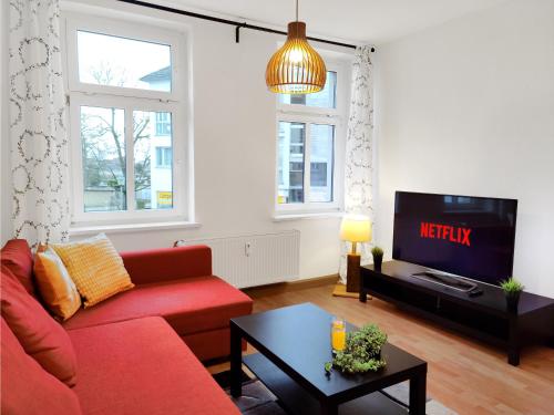 uma sala de estar com um sofá vermelho e uma televisão em Stilvolles Apartment in Leipzig zwischen Flughafen, Messe, Porsche und BMW em Leipzig