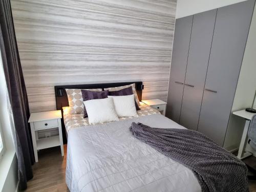 ein Schlafzimmer mit einem Bett mit einer Holzwand in der Unterkunft Upea huoneisto Rauman keskustassa in Rauma
