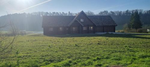 una casa en medio de un campo de hierba en La Maison En Bois, 