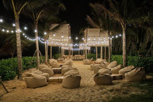 a beach with chairs and palm trees at night at Apec Mandala Mũi Né - Phan Thiết in Phan Thiet