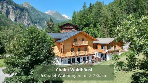 a large wooden house in the mountains with trees at Chalet WaldHäusl luxuriöse Ferienwohnungen mit Sauna & Whirlpool, Kamin, Balkon oder Terrasse mit Bergblick in Heiligenblut