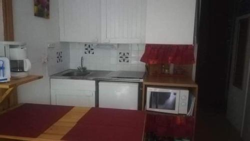 une cuisine avec des armoires blanches et un micro-ondes dans l'établissement Superbe studio aux 7 Laux, à La Ferrière