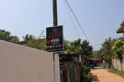 un cartel en una pared al lado de una valla en Double G Motel, en Weligama