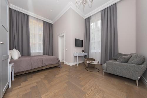 a bedroom with a bed and a couch and a chair at Vila Komoda in Palanga