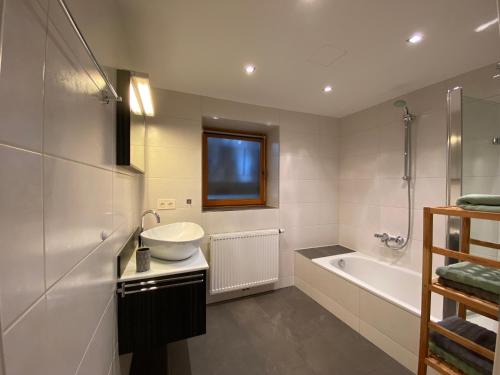 a white bathroom with a sink and a bath tub at Appartement Two in Ötztal-Bahnhof