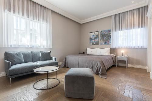 a bedroom with a bed and a couch and a table at Vila Komoda in Palanga
