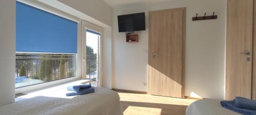 a bedroom with a large window with a view of a balcony at Radikiai House in Smiltynai