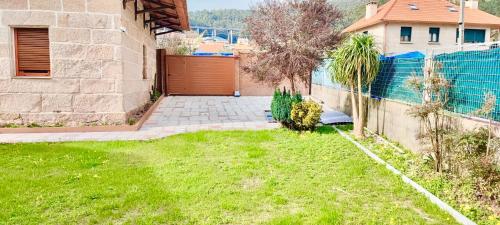 a backyard with a fence and a gate and a yard at Villa a pie de playa in Moaña