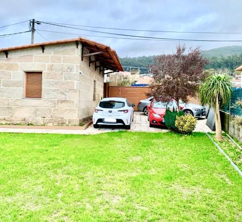 a house with two cars parked in a yard at Villa a pie de playa in Moaña