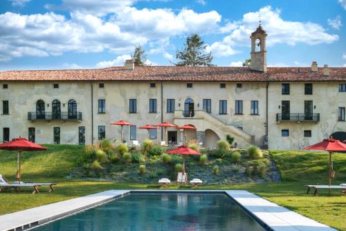 Santa Maria della Versa的住宿－Il Casale Denari，一座带游泳池和红伞的大型建筑