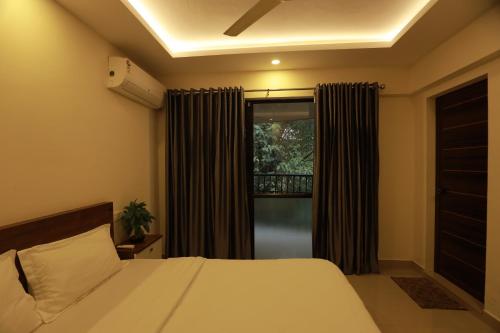 a bedroom with a bed and a window with curtains at VV ROOMS cochin internationalairport in Nedumbassery