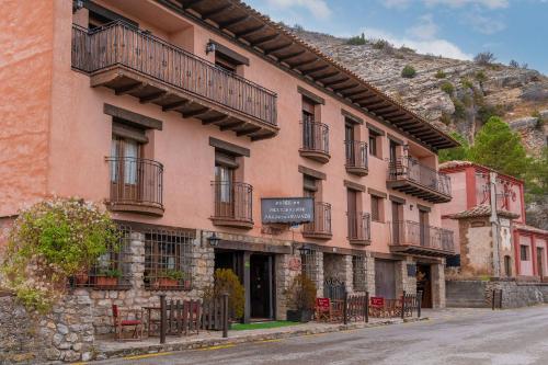 a pink building with balconies on a street at Hotel - Restaurante Prado Del Navazo in Albarracín