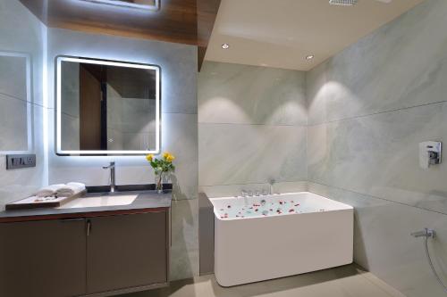 bagno con lavandino bianco e specchio di URBANE BY TREAT a Daman