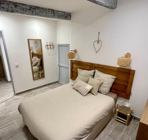 - une chambre avec un grand lit et une tête de lit en bois dans l'établissement Appartement T2 centre village, à Cucuron