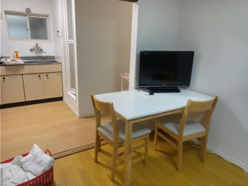a kitchen with a table with a computer on it at アサカヤマ　ゲストハウス in Sakai