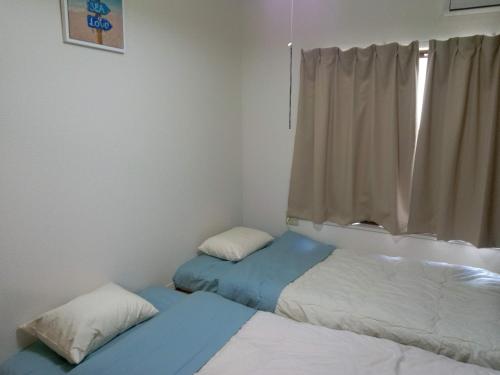 two beds in a room with a window at アサカヤマ　ゲストハウス in Sakai